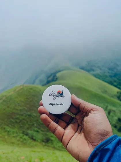Holding our custom Netravati trek badge against the backdrop of the misty green hills. A small memento of a grand adventure.