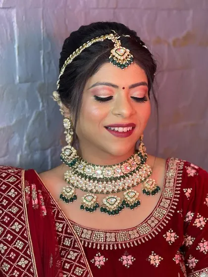 This bride chose a beautiful polki and pearl choker with green drops to match her red velvet lehenga, showing how versatile pastel-accented jewellery can be.