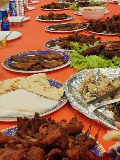 A table overflowing with food. This shot captures the sheer abundance of a traditional Muslim wedding feast, with platters of fried quail, chicken, fish, and naan.
