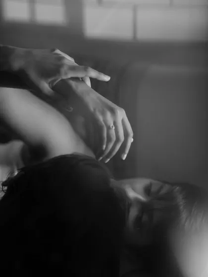 An abstract and intimate black and white close-up of a person's hands and face. The soft, hazy focus creates a dreamy and emotional image that feels deeply personal.
