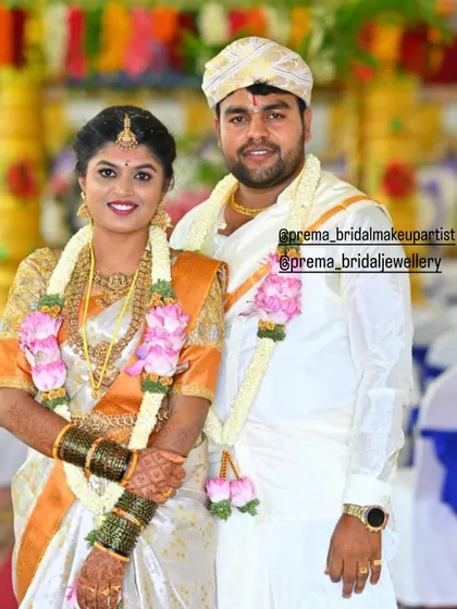 A beautiful couple on their wedding day. The bride is wearing a classic temple jewellery set that complements her white and orange silk saree.