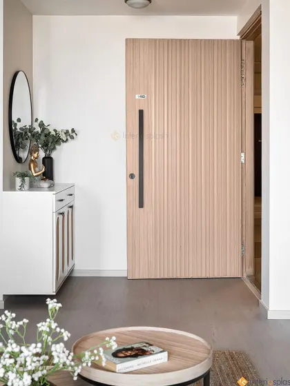 A minimalist and serene entryway. The design includes a simple white shoe cabinet, a round mirror, and a Buddha statue to create a peaceful first impression.