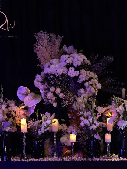 A floral arrangement for a cocktail night in Udaipur, featuring white flowers and candles on a silver stand.