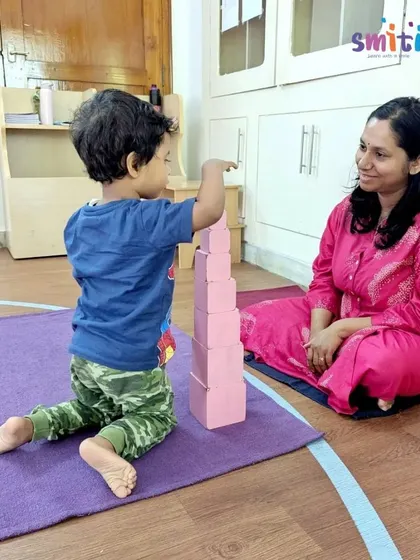 A teacher observes a child as he masters building the Pink Tower. Careful observation allows our teachers to understand each child's developmental stage and needs.