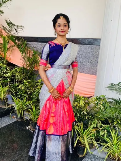 A full view of the pink and silver half-saree lehenga. The combination of a traditional skirt with an embroidered blouse and modern dhavani is very popular.