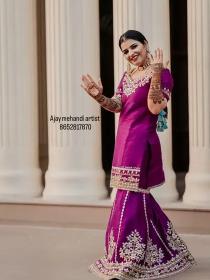A full-length shot of the bride, her hands raised to show the beautiful mehndi that completes her festive look.