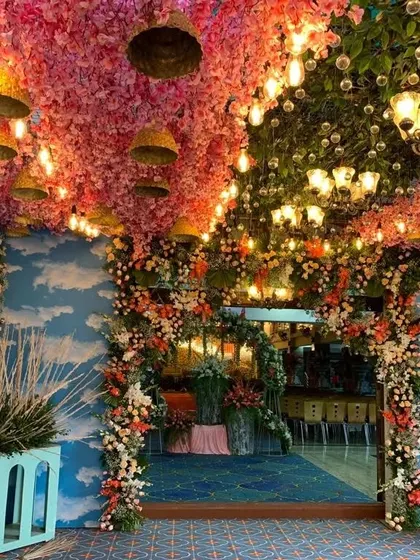 A stunning entrance for a naming ceremony, with a ceiling of pink flowers, hanging lamps, and sky-themed walls creating a fantasy-like atmosphere.