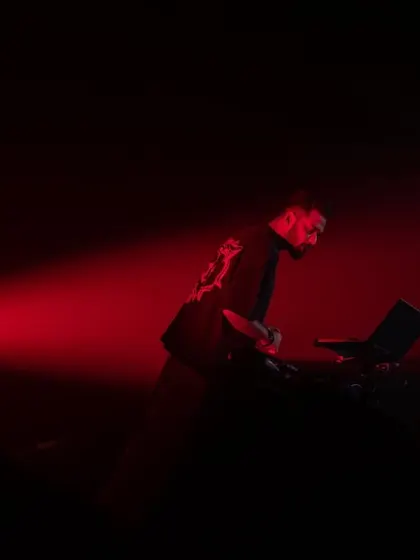A dramatic silhouette under a single red spotlight. Sometimes, less is more when it comes to stage presence.