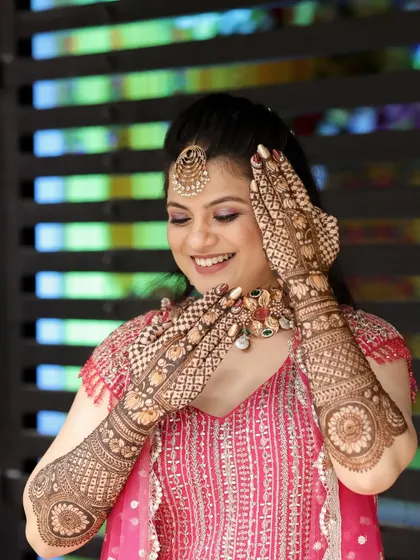 A happy bride admiring her beautiful, detailed mehndi.