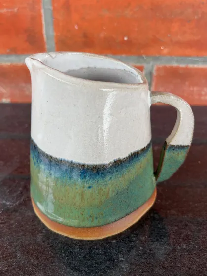 A student's hand-built milk pitcher with a lovely layered glaze effect, created during her 15-day course. The form is both rustic and elegant.