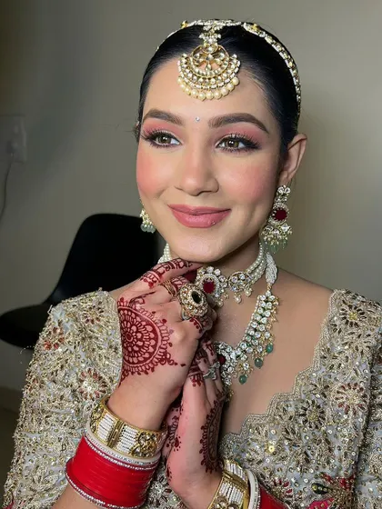 A radiant bridal portrait. The soft pink eyeshadow and nude pink lip create a fresh and modern feel, while the intricate jewelry adds a touch of tradition.