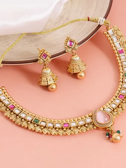 This shot places a traditional necklace set on a plate, with a soft white cloth as a backdrop. The composition is simple and elegant, highlighting the jewelry's beautiful colors and craftsmanship.