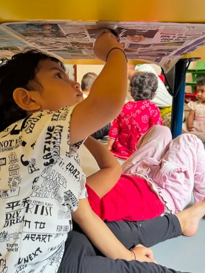 We believe in making learning interesting by changing the environment. Here, a child is completely absorbed in coloring under a table, a simple twist that turns a familiar activity into a new and exciting exploration.