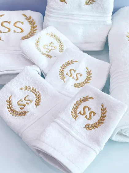A close-up of the luxurious, soft white towels with custom gold embroidery. A practical and elegant gift that the couple can use for years to come.