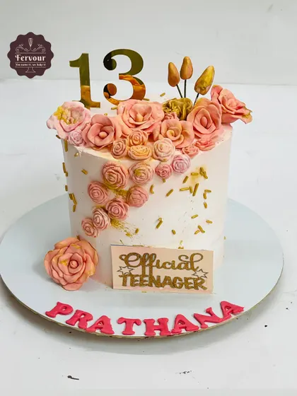 This cake was designed for an "Official Teenager" celebrating her 13th birthday. It features a cascade of handmade fondant roses on a whipped cream base, creating a beautiful and delicate floral design.