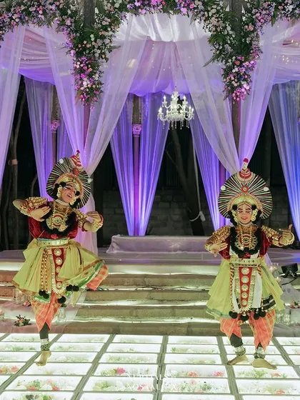 Traditional Yakshagana performers on the floral-filled glass stage, adding a unique and culturally rich element to the Sangeet entertainment.