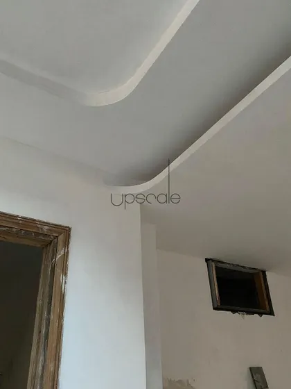 A detail shot of a curved ceiling cove during the finishing stages. This seemingly simple curve requires precise workmanship to achieve a smooth, flawless look, adding a touch of softness to the room's geometry.