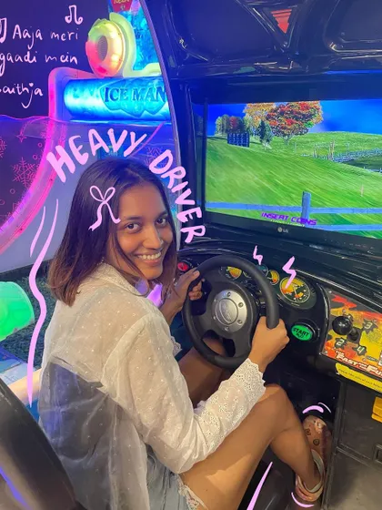 Aaja meri gaadi mein baith ja. A heavy driver moment at the arcade, with a pink bow for a cute touch.