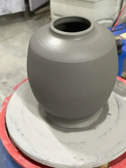 This perfectly rounded vase sits on the wheel just after being shaped. The throwing lines are still visible, a reminder of the hands that formed it.