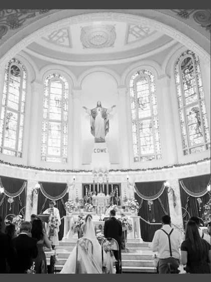 A grand, wide-angle shot of the church ceremony in black and white. This image captures the scale and solemnity of the sacred space and the wedding vows.