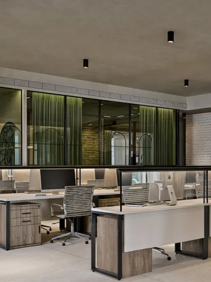 This view shows our open-plan workstation design, separated by low partitions to encourage collaboration while providing personal space. In the background, green curtains behind glass walls add a soft touch of color and texture to the meeting rooms.