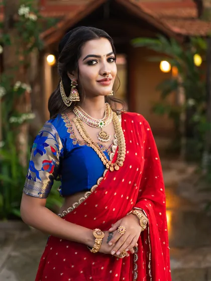 A bold and beautiful look featuring a red saree with a contrasting blue blouse. The smoked-out eye adds a touch of drama and tradition.