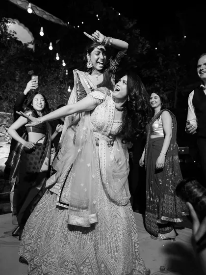 A black and white shot of the bride and her friend sharing a moment of pure, uninhibited joy on the dance floor.