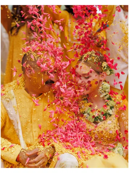 A close-up of the couple being showered with flower petals during their Haldi. These are the colourful, happy memories that make Indian weddings so special.