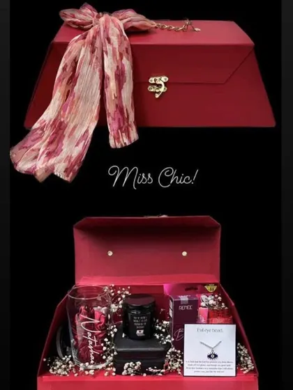 The "Miss Chic" hamper is for the stylish woman in your life. It comes in a reusable red trunk-style box and includes a personalized glass, a scented candle, an evil eye necklace, and a beautiful scarf.