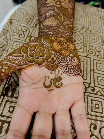 A close-up of the palm, showing the groom's name "Ali" written in a beautiful floral frame.
