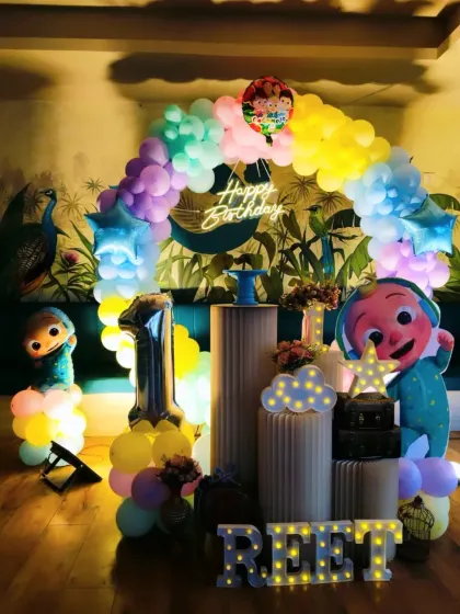 We designed this charming Cocomelon setup for Reet's first birthday. It features a pastel rainbow balloon arch, a "Happy Birthday" neon sign, and character cutouts, perfect for a smaller, more intimate celebration.