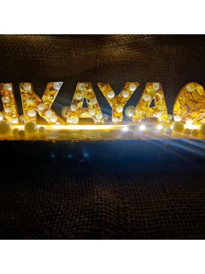 The custom LED name stand, glowing warmly in the dark. The light shines through the preserved flowers, creating a magical and personal piece of decor.