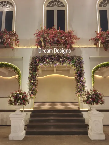 A symmetrical and elegant entrance setup. The central floral arch is flanked by two smaller arches and large floral urns, creating a balanced and picture-perfect welcome.