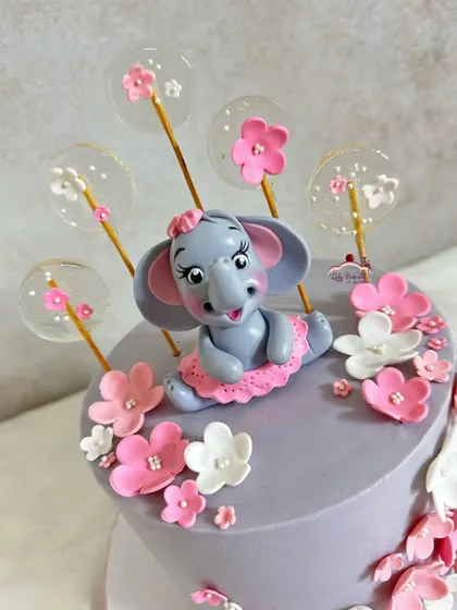 A close-up of the hand-sculpted elephant topper, surrounded by delicate, translucent lollipops.