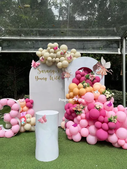 For this 'Young, Wild & 30' birthday, we created a whimsical fairy and butterfly theme. The setup includes a personalized arched backdrop, a vibrant balloon cascade in pinks and oranges, and a custom balloon number display.
