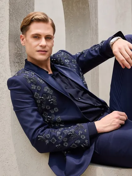 Elegance stitched in tradition. This relaxed pose highlights the fit and comfort of the bespoke jacket, proving that you don't have to sacrifice ease for style. The detailed embroidery on the shoulder is a mark of true craftsmanship.
