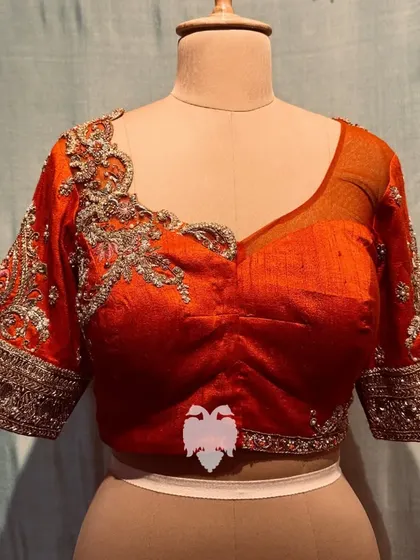 The front of the orange blouse, blending modern style with traditional craftsmanship.