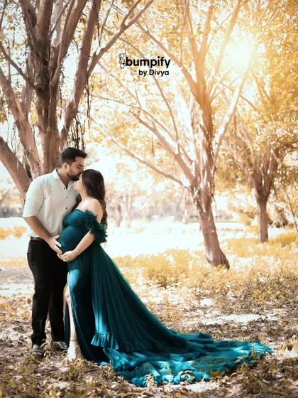 A tender kiss shared between the couple during their golden hour outdoor shoot. The warm sunlight filtering through the trees creates a dreamy and romantic atmosphere.