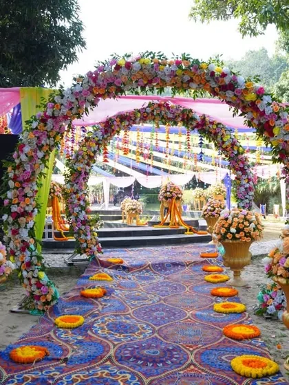 A closer look at the grand floral arches and patterned aisle runner at a vibrant outdoor Mehendi event.
