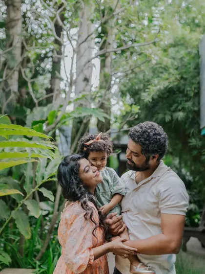 A family shares a hug amidst the trees. The natural, green background provides a beautiful and serene setting for this loving moment.