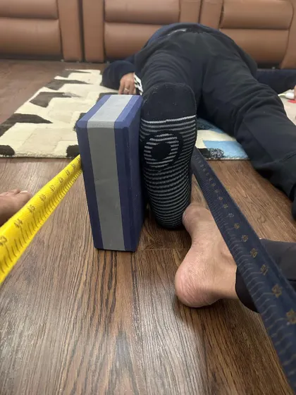 A glimpse into a therapy session. Here, I am using belts and blocks to precisely measure and correct alignment in the legs and hips. This detailed work is crucial for addressing the root cause of musculoskeletal pain.
