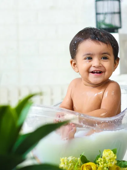 This candid shot captures a moment of happiness and play during a milk bath session, framed beautifully by a foreground plant.