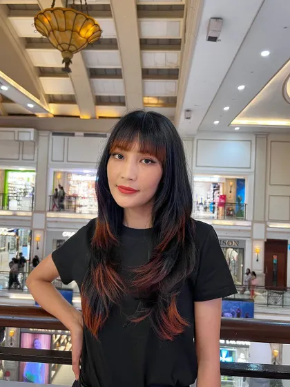 An edgy wolf cut with colored ends. The tips are dyed a fiery red-orange, adding a bold and creative touch to the layered haircut.