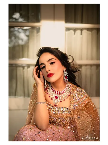A close up portrait showcasing the beautiful ruby and diamond jewelry. The makeup is classic and clean, with a bold red lip that perfectly complements the precious stones.