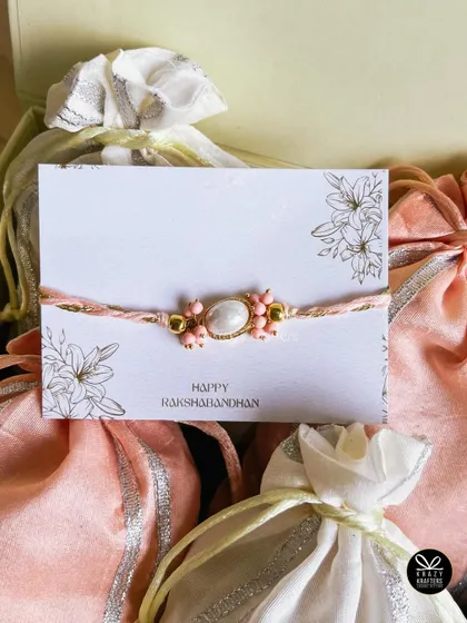 A delicate and pretty rakhi for a sister, surrounded by elegant potlis from our 'Rakhi Saga' collection.