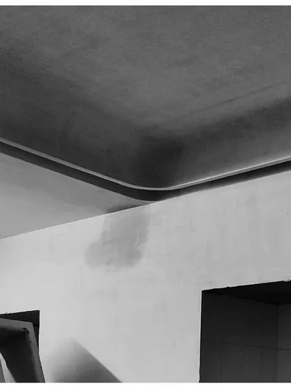 The junction of a curved ceiling and a wall, captured in its raw construction phase. This image highlights the underlying geometry and form that we use to create serene and minimalist interiors.