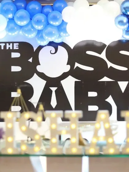 A close-up of the Boss Baby backdrop, showing the sharp, graphic style of the theme. The 'Happy Birthday' neon sign adds a modern touch.