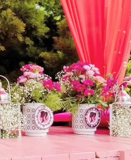 Detailed table decor for the Barbie party, including lanterns filled with baby's breath and vases with the iconic Barbie logo.