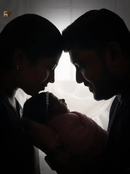 A beautiful silhouette of a mother and father holding their newborn, their heads bowed together in a moment of love. This artistic shot is a powerful representation of new family bonds.