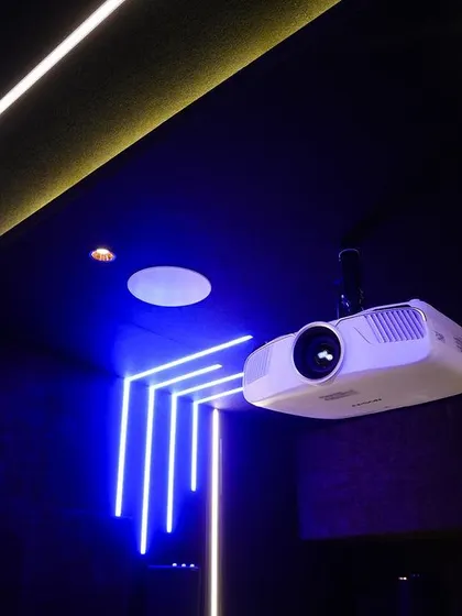 A close-up of the ceiling-mounted Epson projector and the geometric blue neon light feature.